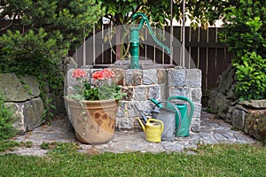 Well in a summer garden with potted flowers and watering cans