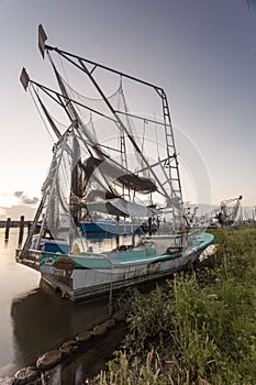 Well worn shrimping boat docked on a shore in the bayou