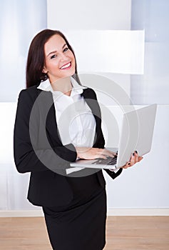 Welldressed businesswoman using laptop in office