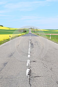 Welling, Germany - 05 09 2021: straight road with potholes and cracks in spring landscape
