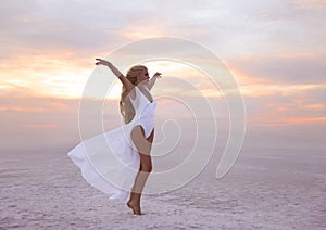 Wellness. Beautiful free confidence woman in white swimsuit enjoy summer vacation at sunset on the beach. Carefree blonde girl st