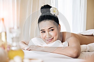 Wellness, beauty and relaxation concept; young Asian woman lying at spa bed