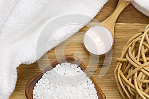 Wellness candle on a wooden spoon with towel and bath salt photo