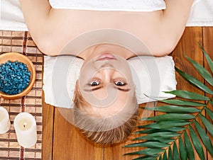 Wellness center. Girl lies on massage table, beside salt and spa accessories