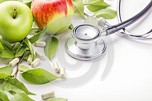 Wellness concept Stethoscope, apple, and pills arranged on white backdrop