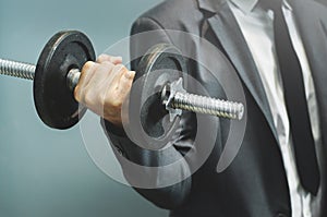 Wellness, healthy concepts. Businessman lifting dumbbell at office.