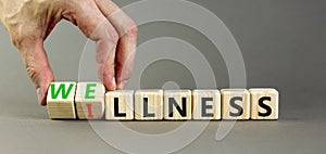 Wellness or illness symbol. Concept words Wellness and Illness on wooden cubes. Doctor hand. Beautiful grey table grey background