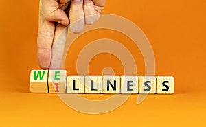 Wellness or illness symbol. Concept words Wellness and Illness on wooden cubes. Doctor hand. Beautiful orange table orange