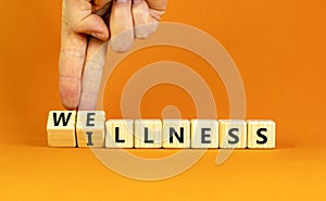 Wellness or illness symbol. Concept words Wellness and Illness on wooden cubes. Doctor hand. Beautiful orange table orange