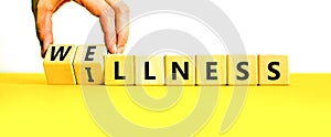 Wellness or illness symbol. Concept words Wellness and Illness on wooden cubes. Doctor hand. Beautiful yellow table white