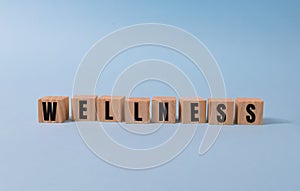 Wellness sign with wooden cubes on blue background.