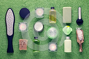 Wellness and spa products, laser feet grater, cream, lotion, soap, pink salt and candle on green towel