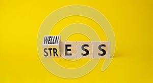 Wellness and Stress symbol. Turned Wooden cubes with word Wellness and Stress. Beautiful yellow background. Business and Wellness