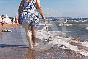 Wellness walk of an old woman with a cane along the sea beach