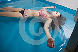 Wellness - young woman floating in Spa or swimming pool, she is very relaxed. Copy spase.