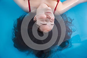 Wellness - young woman floating in Spa or swimming pool, she is very relaxed. Top view.