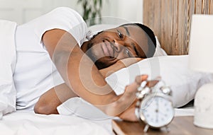 Wellslept Black Man Turning Off Alarm-Clock Waking Up In Bedroom