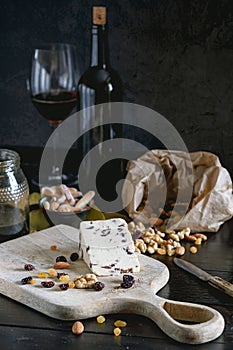Wensleydale cheese with cranberries, red wine, honey, nuts, raisins on wooden cutting board