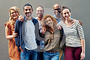 Were become quite close as a team. Portrait of a group of people standing together against a wall outside.