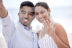 Were getting married. Cropped portrait of a young, newly betrothed couple showing off their engagement on the beach.
