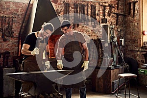 Were the heavy metal guys. two handsome young metal workers working together inside a welding workshop.