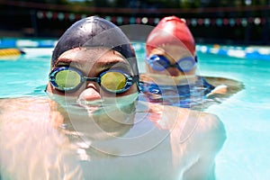 Were at home in the water. Two young swimmers with their faces half subrnerged in the water.