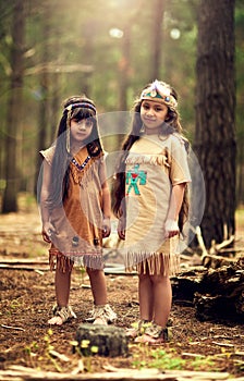 Were Indians for the day. Full length portrait of two little girls playing dressup in the woods.