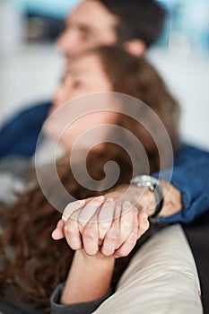 Were in this life together. a young couple holding hands while relaxing on the sofa at home.