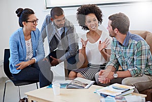 Were making progress. Shot of a group of designers having a meeting around a coffee table.