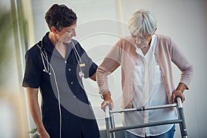 Were slowly getting there. a young female nurse assisting a senior woman walk using a walker in a nursing home.