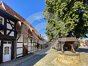 Wernigerode, Germany, July 2022 : a characteristic vintage old well at forking street with a tall tree behind, landmark