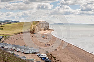 08-29-2020 West Bay, UK. View from clifftop at a golden beach with people enjoying walking and coastline of West Bay.