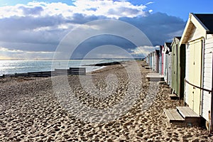 West Mersea beach with beach huts and dark threatening cloud.