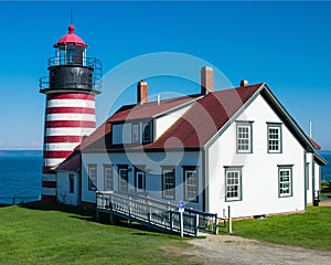 West Quoddy Head Lighthouse and a house near it in Maine, USA under the blue sky