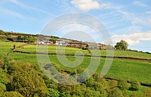 West yorkshire dales scenery with farmhouses on high hills with typical walled fields and moors in the distance