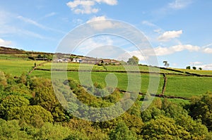 West yorkshire dales scenery with farmhouses perched on high hills with typical walled fields and midgley moor in the distance