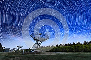 The Westerbork Synthesis Radio Telescope WSRT during dusk, with a light cloudy sky and stars a little visible