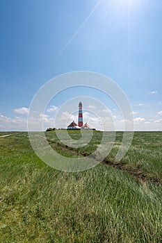 Westerhever Lighthouse standing tall in a sunny field, Baltic Sea, Germany