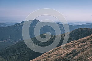 Western carpathian mountain tops in autumn covered in mist or clouds with blue cast and multidimensional lines - vintage old film