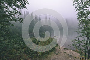 Mlhavé ráno pohled v mokré horské oblasti ve slovenských Tatrách. panorama horského jezera - vzhled vintage filmu