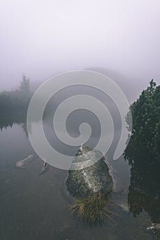 Misty morning view in wet mountain area in slovakian tatra. mountain lake panorama - vintage film look