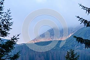 Mountain tops in autumn covered in mist or clouds in sunrise li