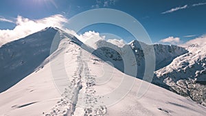 Mountain tops in winter covered in snow with bright sun and blue