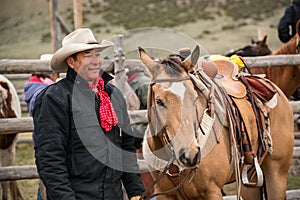 Western cowboy with saddled buckskin horse ready to go roundup horses