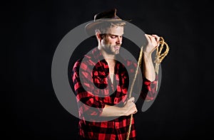 Western life. Man unshaven cowboy black background. Man wearing hat hold rope. Lasso tool of American cowboy. Lasso is