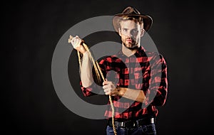 Western life. Man unshaven cowboy black background. Man wearing hat hold rope. Lasso tool of American cowboy. Lasso used