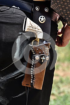 Western pistol gun with ivory handle grip in leather holster gun belt worn by old west cowboy