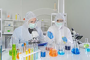 A western scientists couple working on test tube to analysis and develop vaccine of covid-19 virus in lab or laboratory in