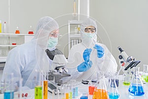 A western scientists couple working on test tube to analysis and develop vaccine of covid-19 virus in lab or laboratory in