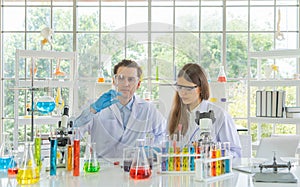 A western scientists couple working on test tube to analysis and develop vaccine of covid-19 virus in lab or laboratory in